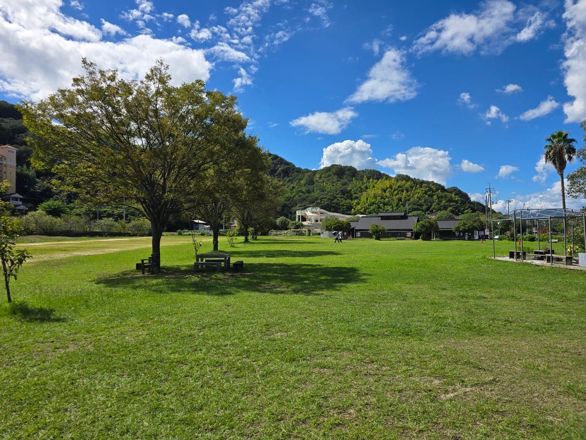 因島アメニティ公園の芝生広場（木陰にテーブルとベンチあり）