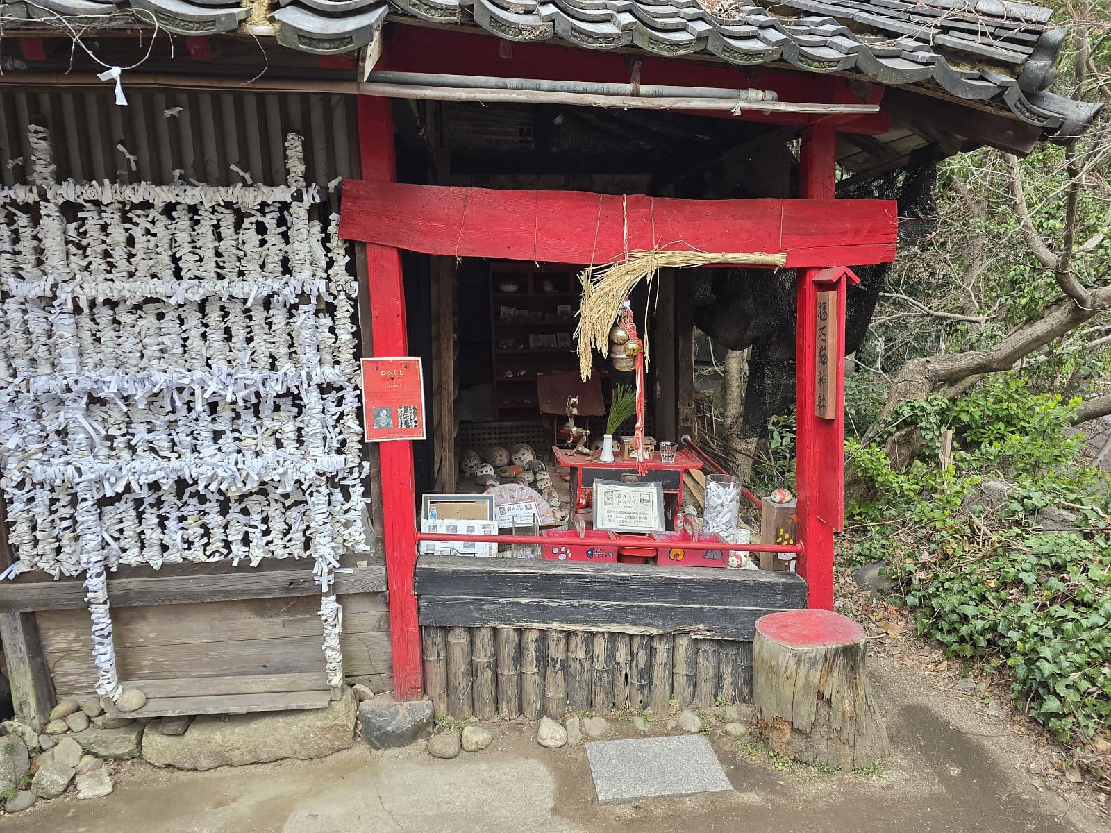 福石猫神社の祠——赤い鳥居と白いお守りが数十本吊るされた小さな社