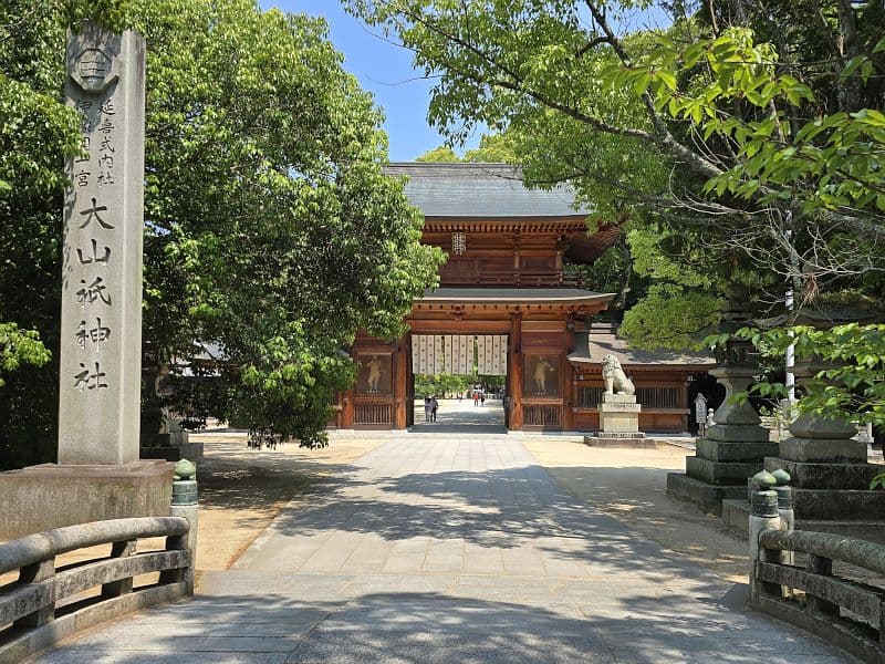 大山祇神社の参道。楠の大木が両側を覆い、奥に社名碑と総門が見える石畳の参道