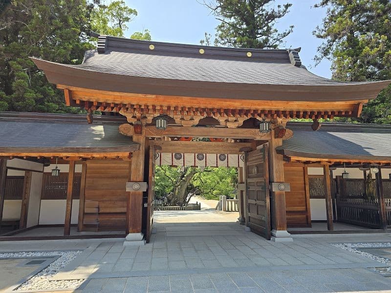 大山祇神社の神門（内拝殿への入口）。天然木の門柱と朱色の装飾、奥に御神木の楠が見える