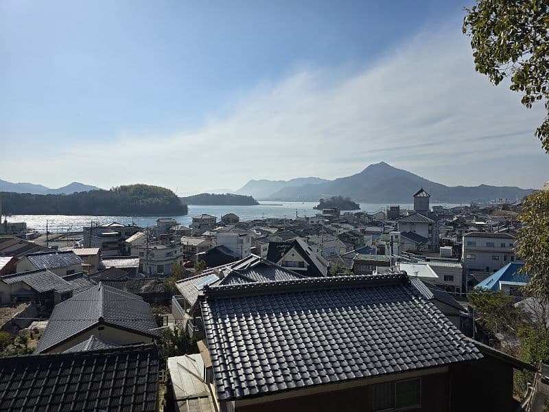 見張台からの眺望。因島の街並みと瀬戸内海、遠くに山々のシルエットが連なる