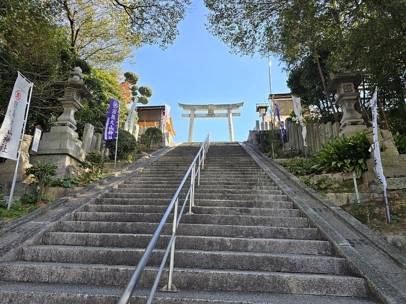 因島大山神社の参道石段。青空に向かって伸びる石段の両脇に石燈籠が並ぶ