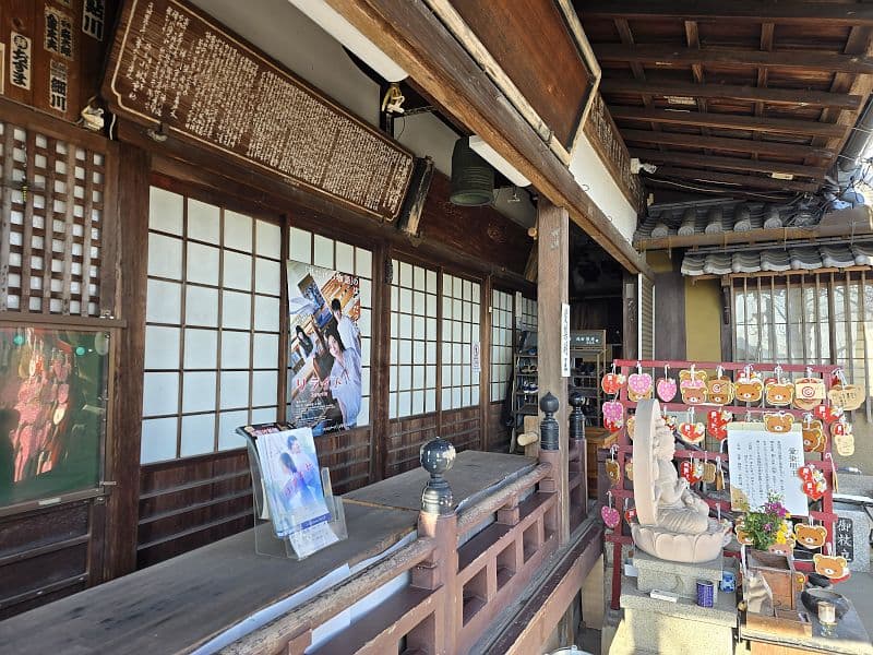 千光寺本堂の縁側。梵鐘の下に観音像と色とりどりの絵馬が並ぶ