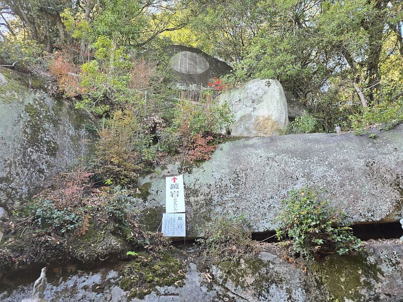 千光寺の鏡岩。木々の間にそびえる花崗岩の巨岩と案内板