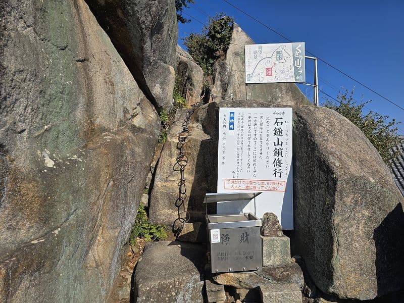 千光寺・石鎚山鎖修行の入口。案内板と鎖、賽銭箱が並ぶ