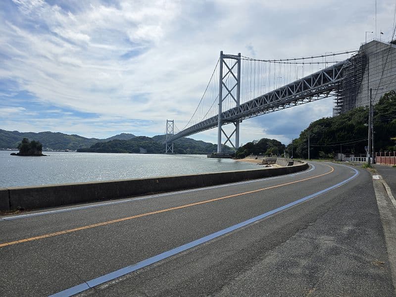 因島大橋を真下から見上げる。サイクリングロードの青いラインと瀬戸内海