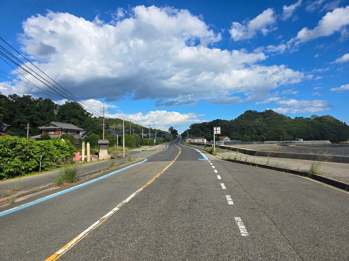 生口島の南岸を東へ延びる道(左に民家、右に海沿いの堤防)